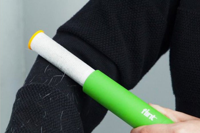 Person using the Flint Reusable Lint Roller on their sweater arm.